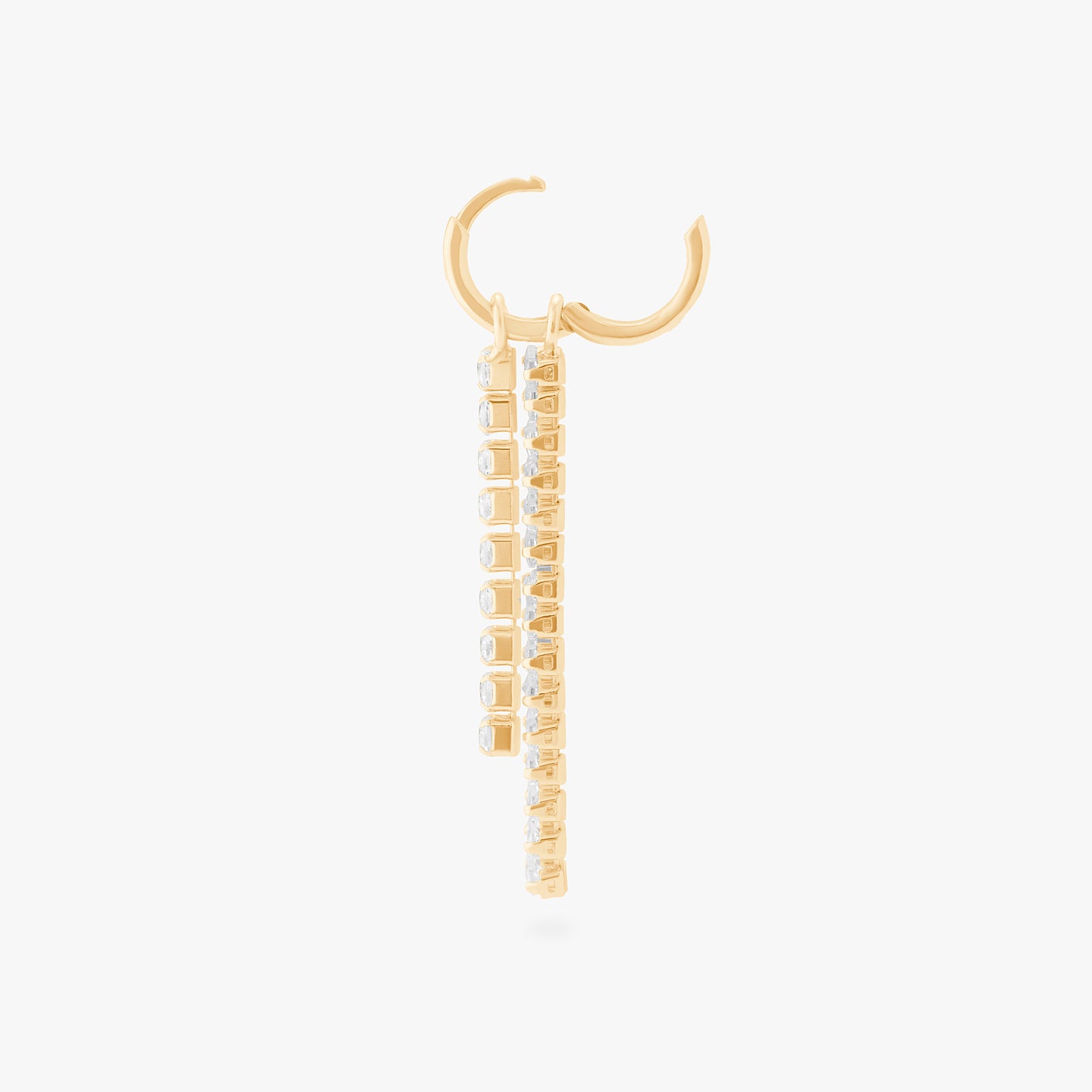 This is an image of a gold small slim huggie with a charm that consists of a string of gold/clear CZs, and a charm that consists of gold/clear baguette CZs unhinged. color:null|gold/clear