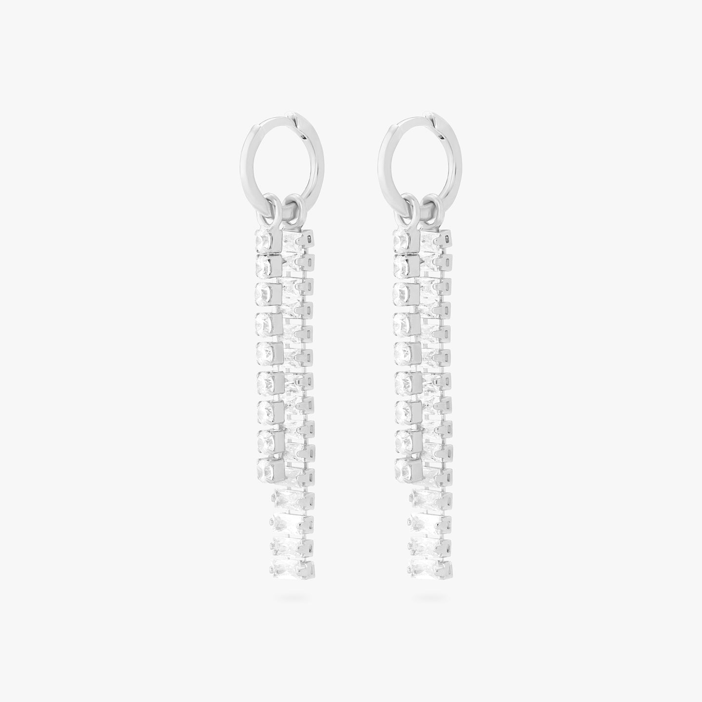 This is an image of a pair of silver small slim huggies with a charm that consists of a string of silver/clear CZs, and a charm that consists of silver/clear baguette CZs. [pair] color:null|silver/clear