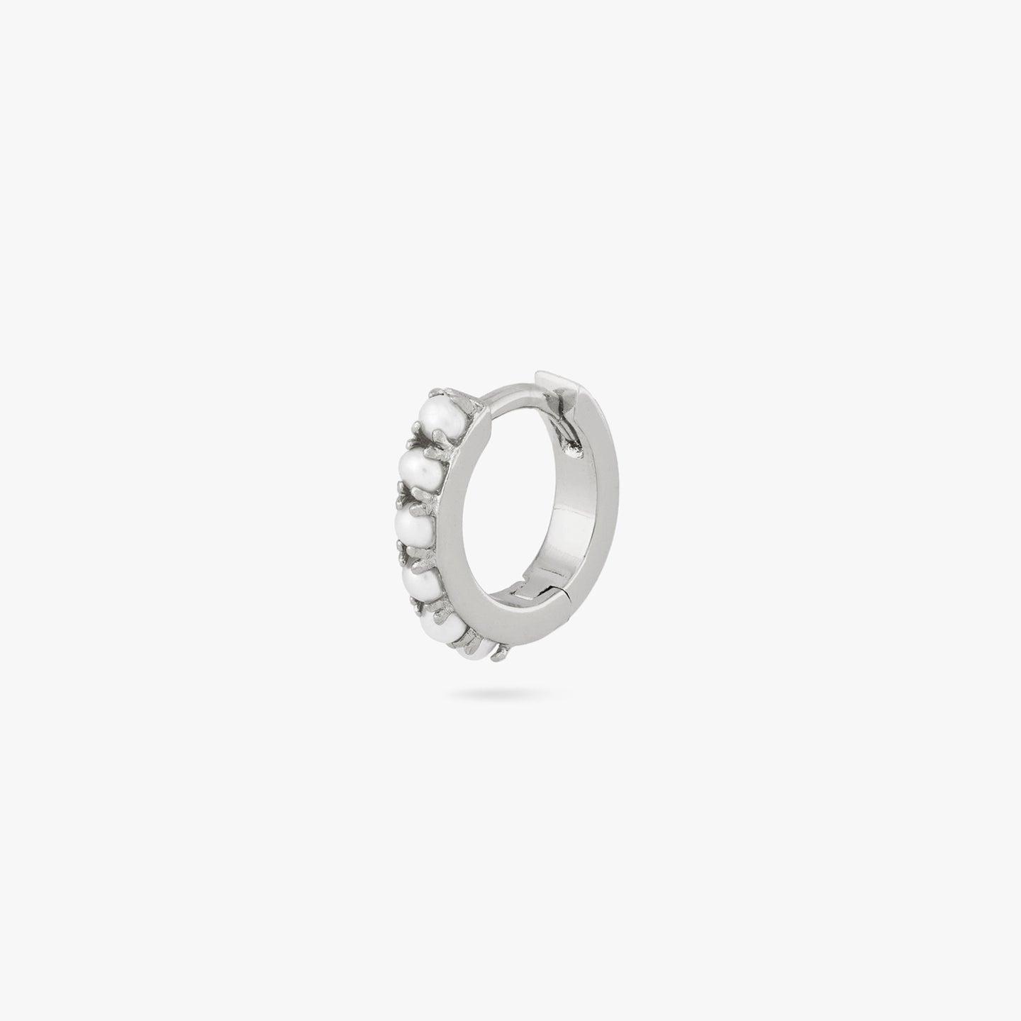 This is a small silver huggie that has small pearls lining the front of it color:null|silver