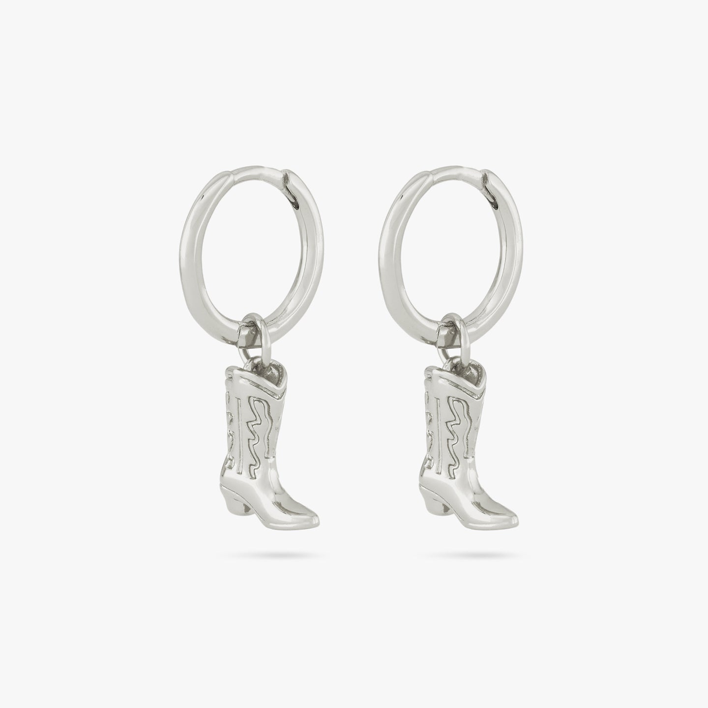 This is a pair of silver cowboy boot charms dangling from silver huggies [pair] color:null|silver