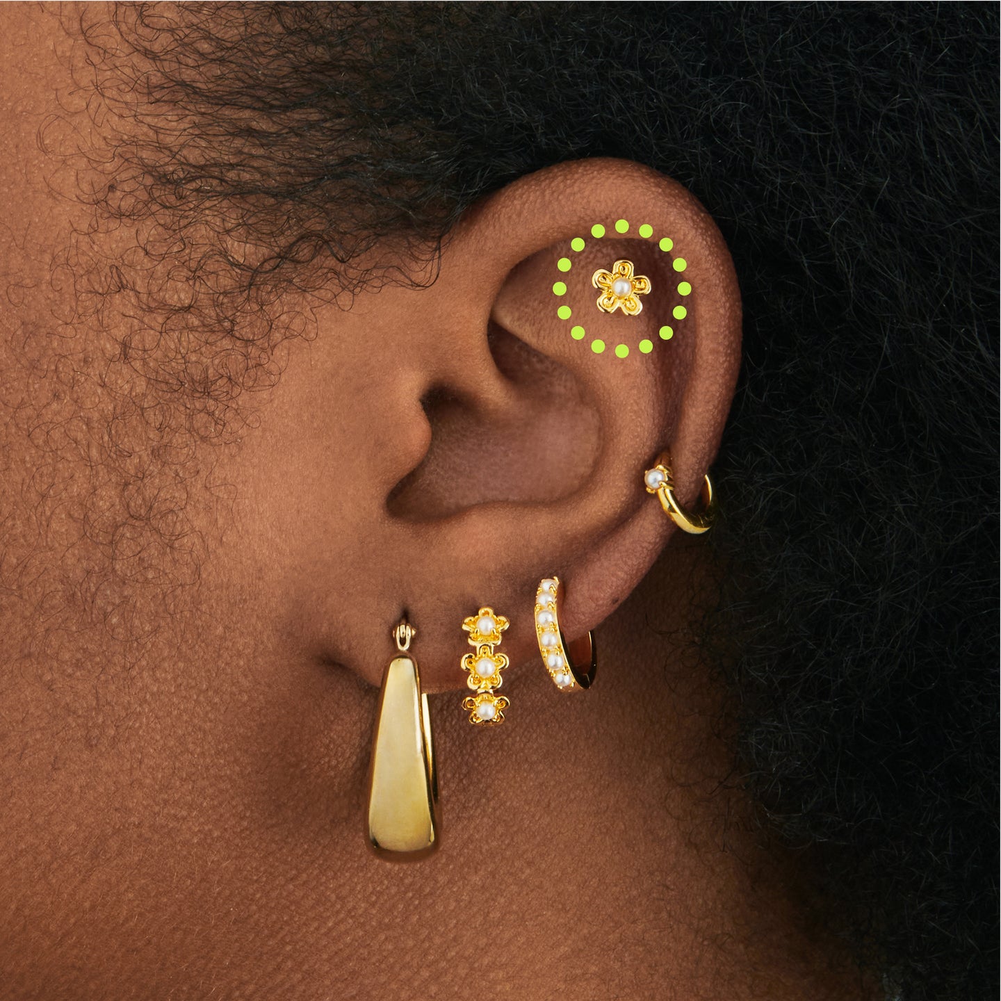 a gold daisy shaped stud set with a pearl on ear [hover] color:null|gold
