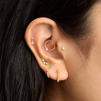 This is an image of a 14k gold flatback stud with 3 clear cz bezels in a cluster shape on ear. [hover] color:null|14k gold/clear