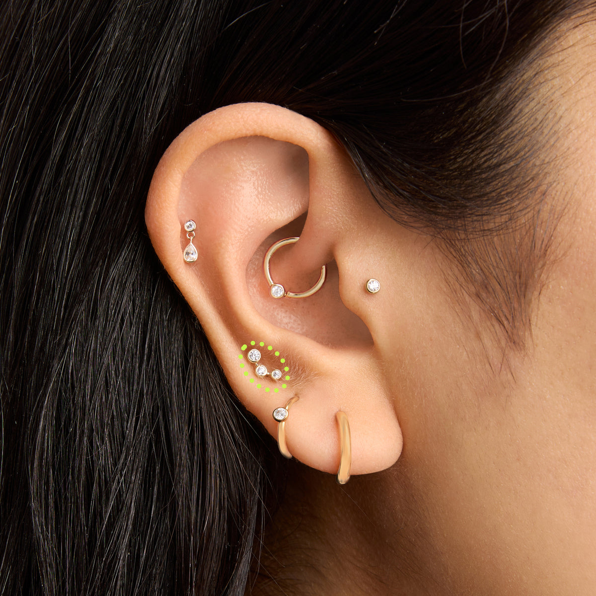 This is an image of a 14k gold flatback stud with 3 clear cz bezels in a cluster shape on ear. [hover] color:null|14k gold/clear