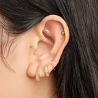 This is an image of a 14k gold flatback that is shaped as a twinkle star with a clear cz and clear cz bezel dangling from it on ear. [hover] color:null|14k gold/clear