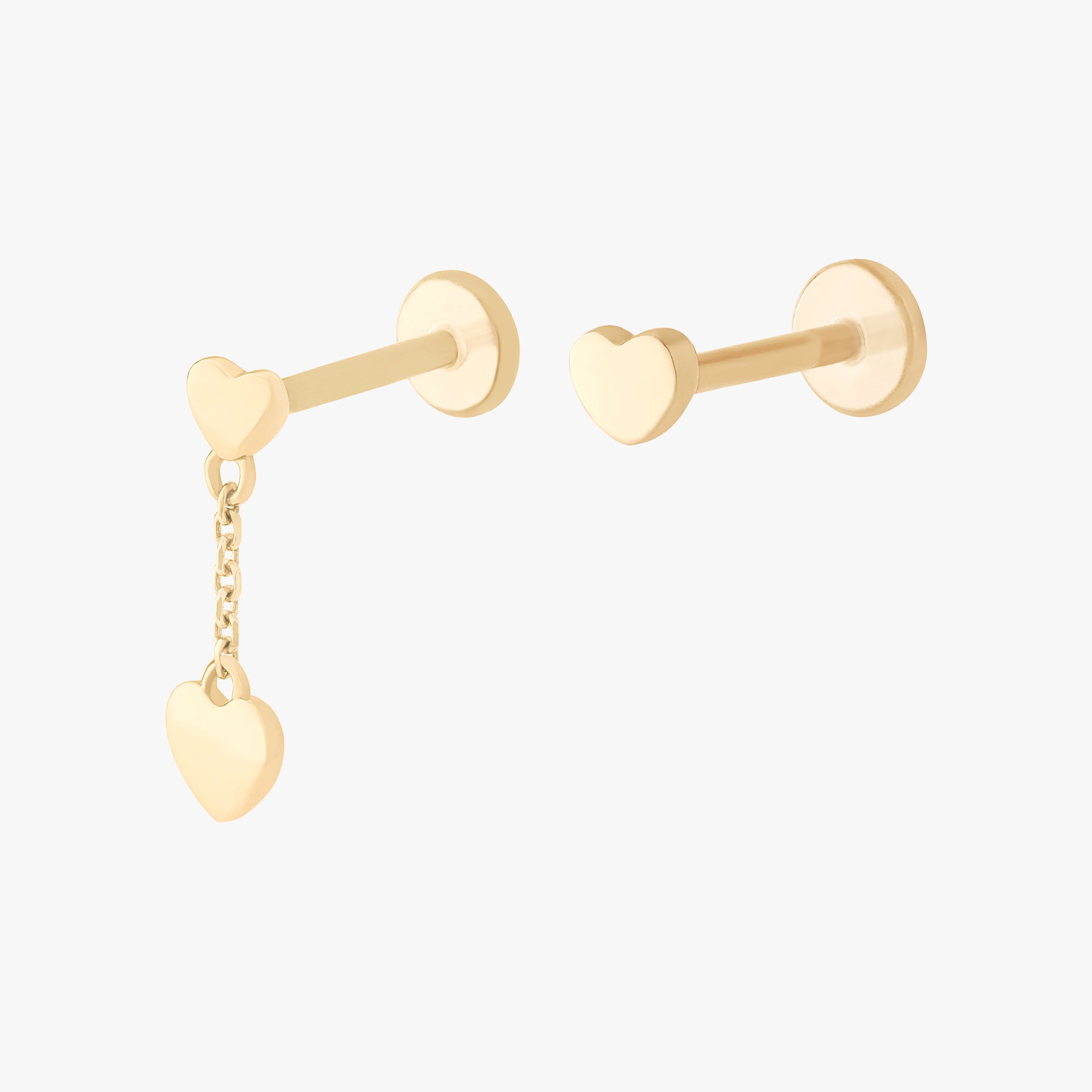 This image shows a set of earrings. This set contains one 14k Yellow Gold heart dangle flatback stud and a 14k Yellow Gold heart flatback stud