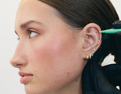 Close-up of a person's ear with multiple ear piercings getting an ear piercing consultation.
