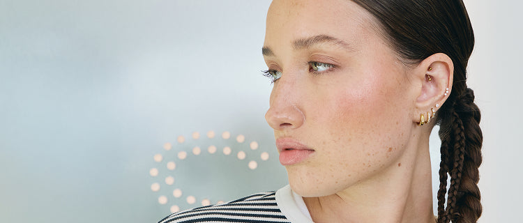 Woman with braided hair wearing gold earrings against a light background