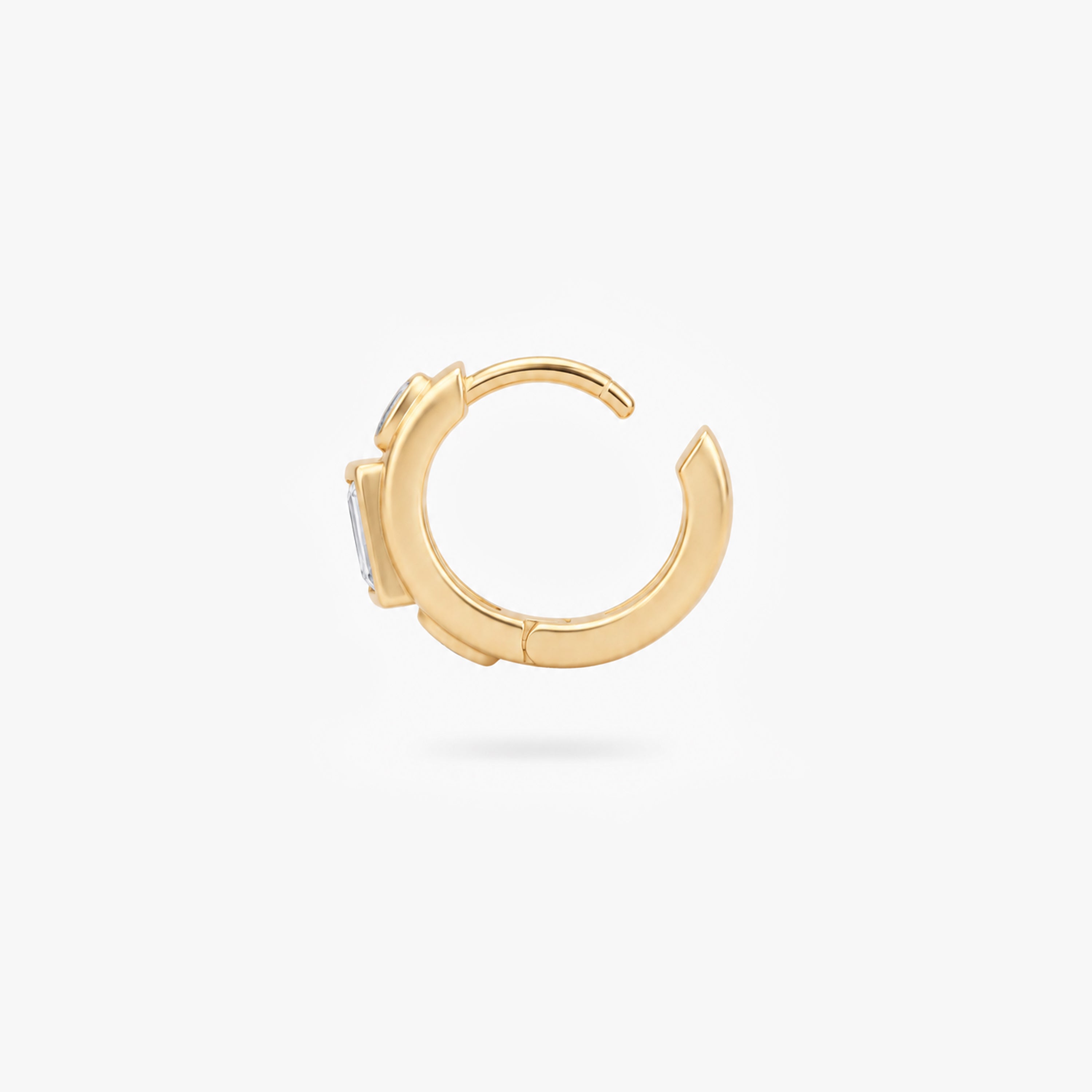 This image shows the profile view of a 14k gold plated huggie with three clear cz stones. One square in the middle and two circular stones on the outside. - Alternative view 2
