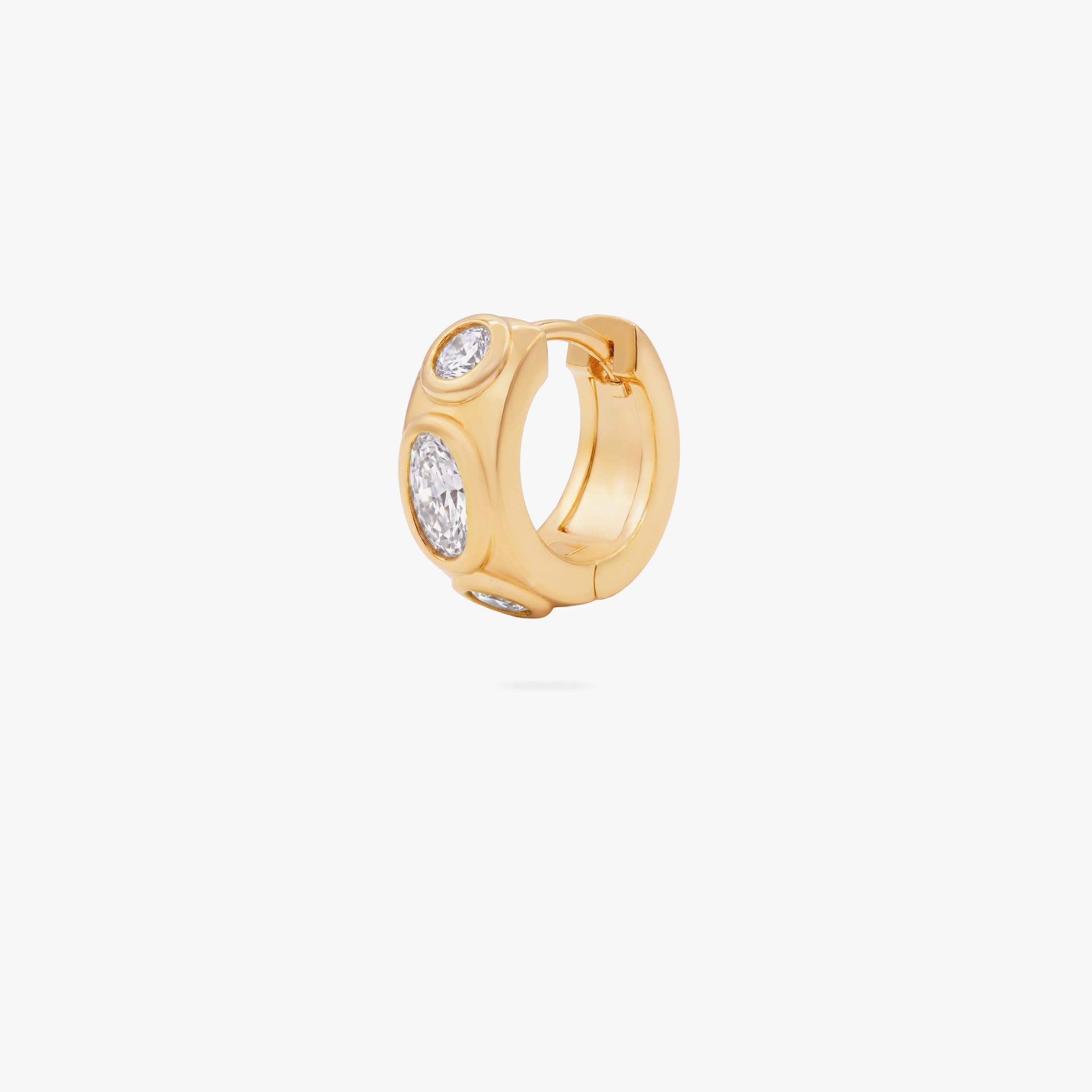 this image shows the front of a 14k gold plated huggie with three clear circular cz stones - Main view