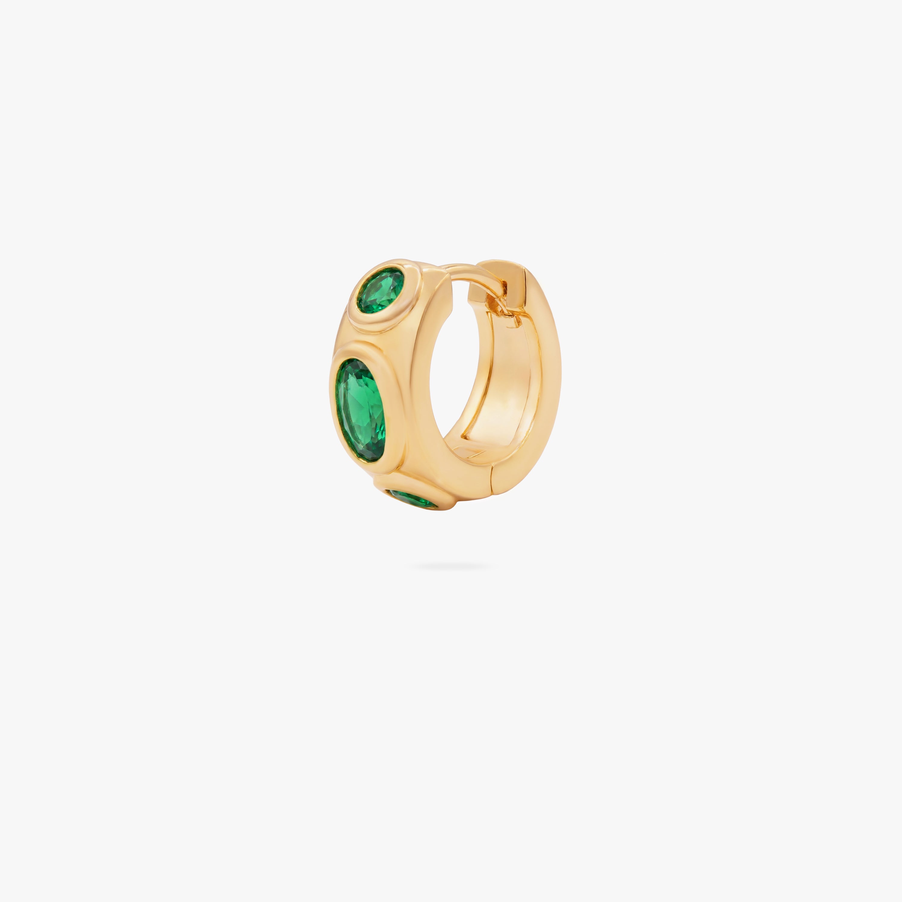 this image shows the front of a 14k gold plated huggie with three green circular cz stones - Main view