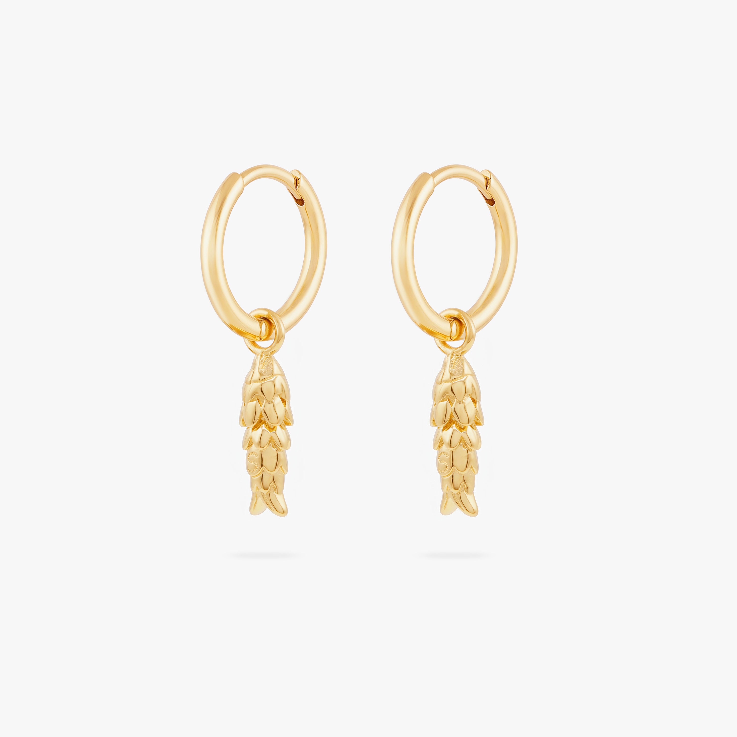 This image shows a pair of  14k gold plated huggies with dangling fish charms