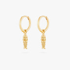 This image shows a pair of  14k gold plated huggies with dangling fish charms