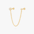 this image shows a titanium gold chain connector earring featuring a circular CZ flatback stud and a circular clear cz stud flatback linked by a delicate gold chain