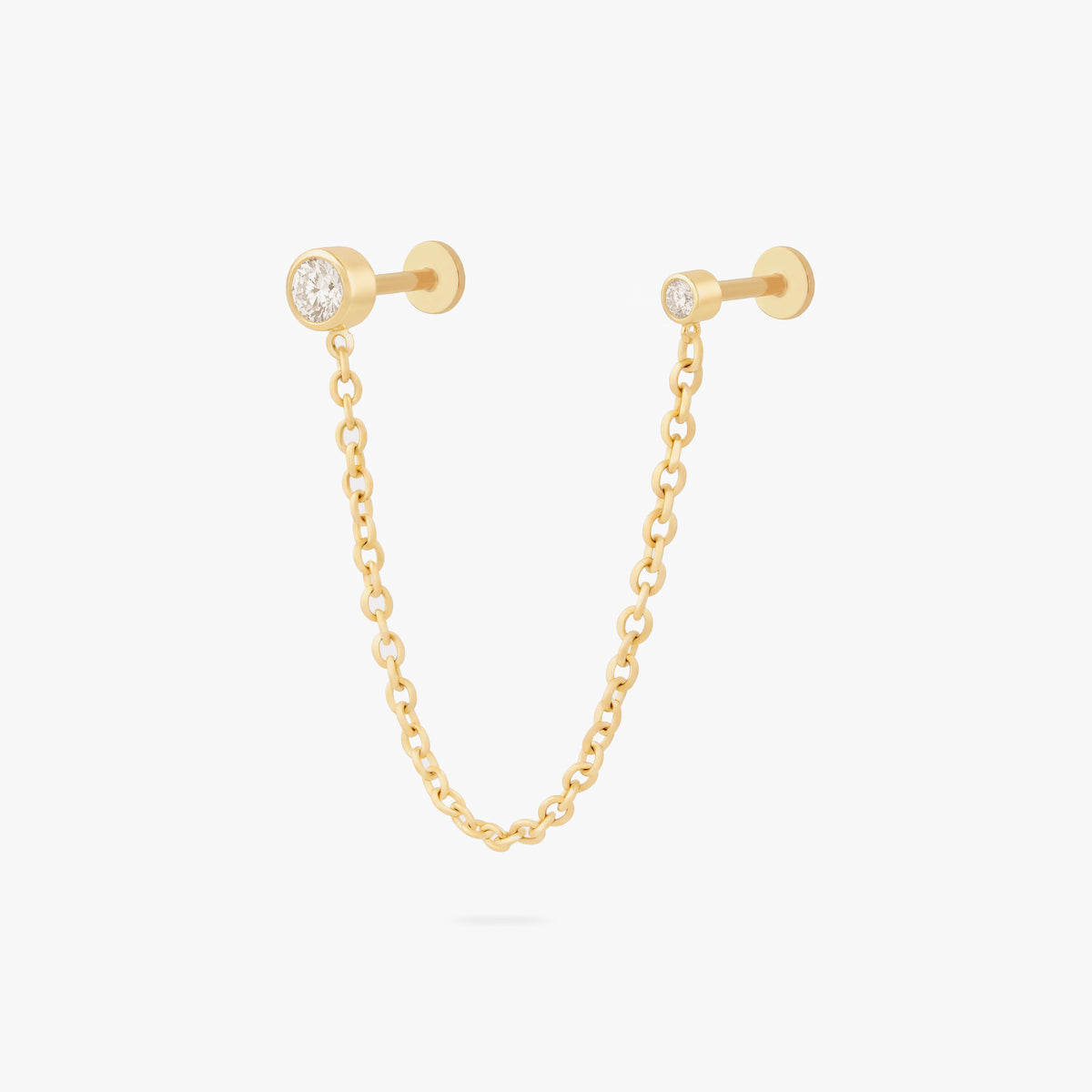 this image shows a titanium gold chain connector earring featuring a circular CZ flatback stud and a circular clear cz stud flatback linked by a delicate gold chain