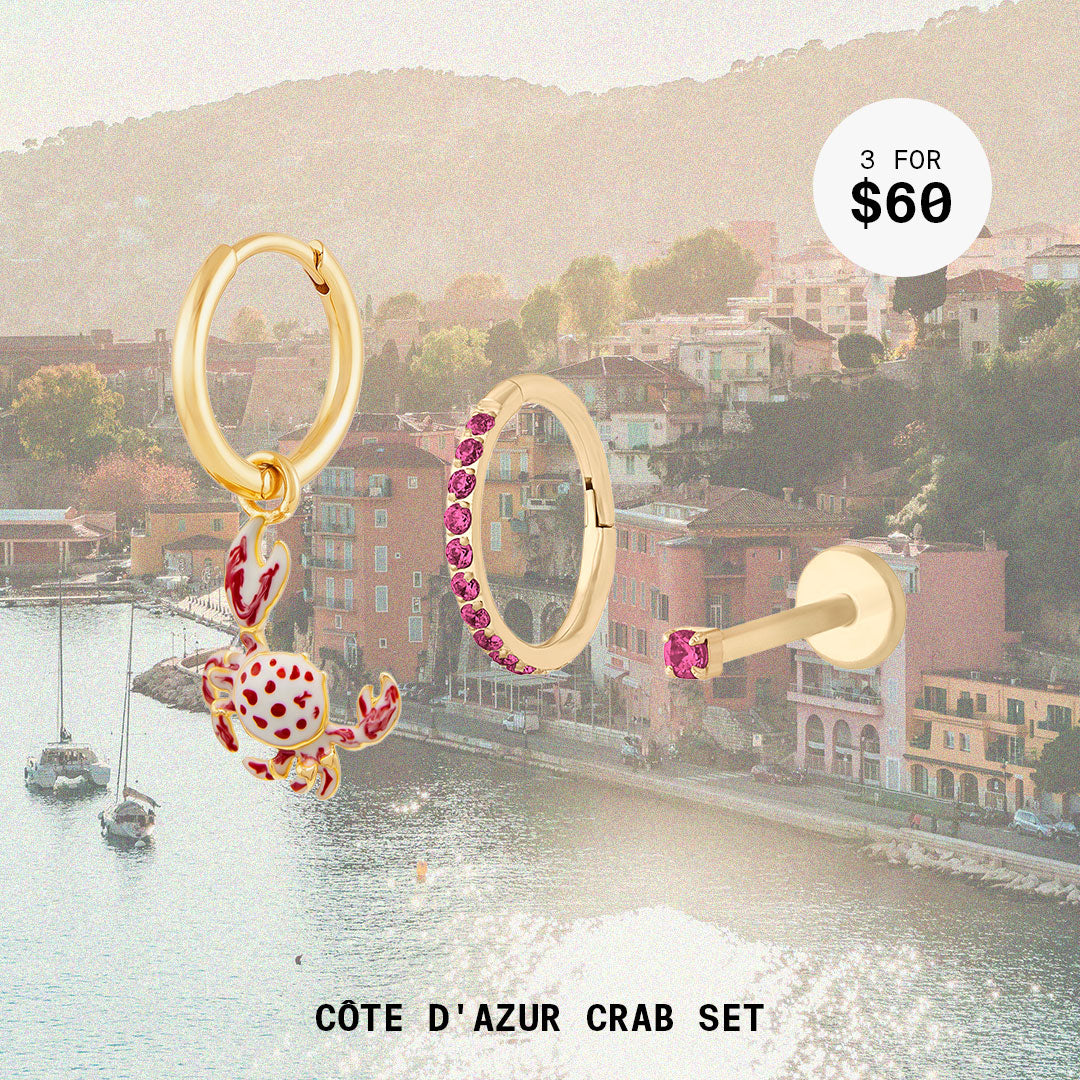 This image shows a landscape background with a set of three earrings. This set includes a crab huggie, micro cz flatback Stud, and Pave Clicker. All earrings in this set are 14k gold plated.