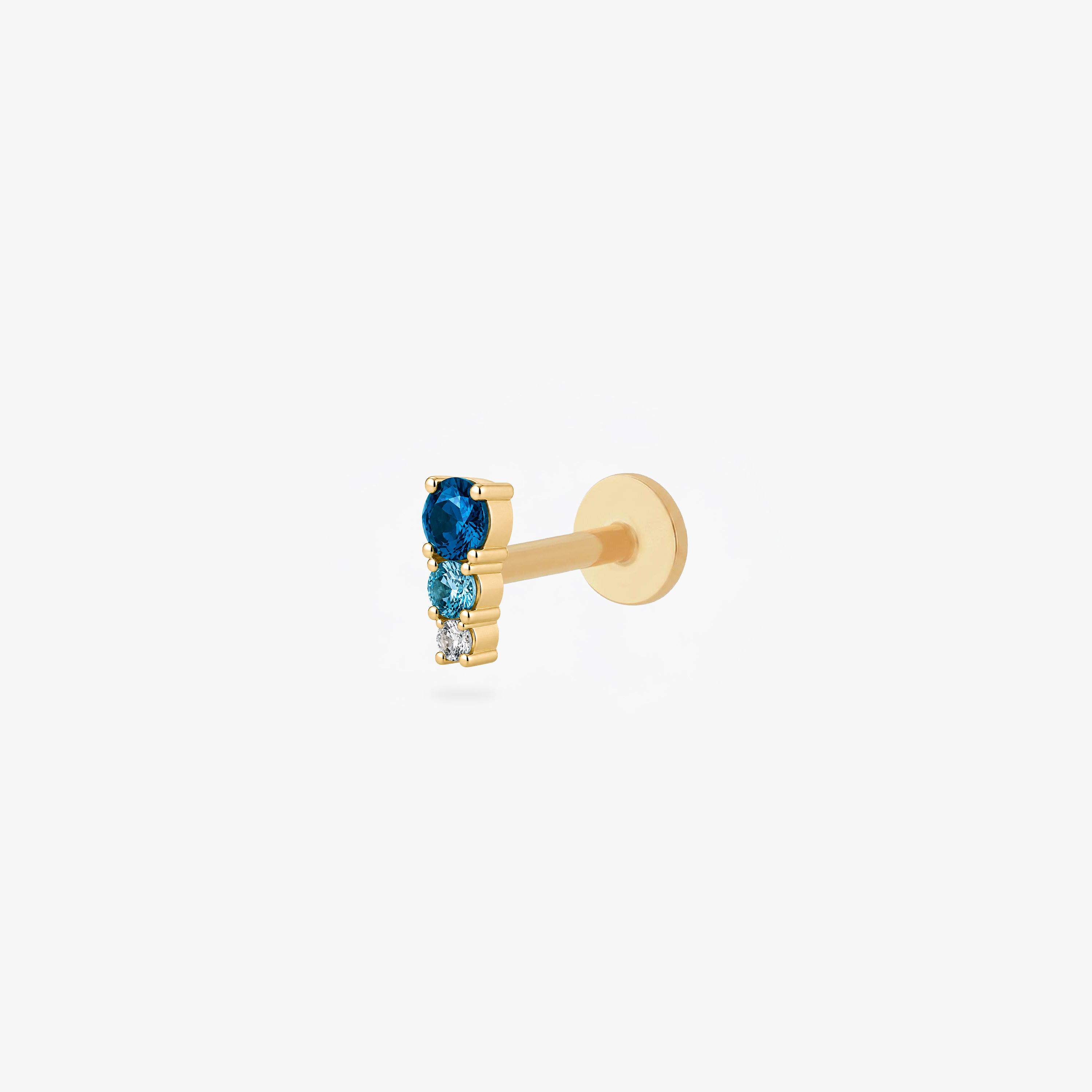 This image shows a side angle of a Golden titanium flatback with three cz stones. the top one is a dark blue, the middle a light blue and the bottom cz is clear. - Main view