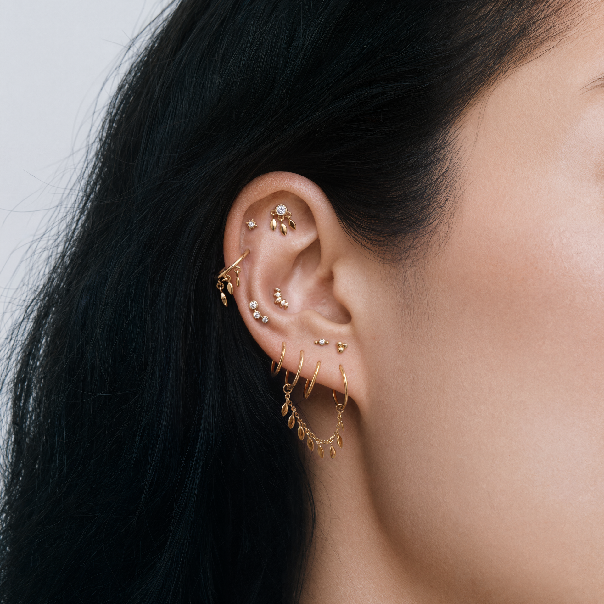 This image shows an earscape with gold earrings including the bezel fringe flatback, fringe clicker and the fringe connector chain