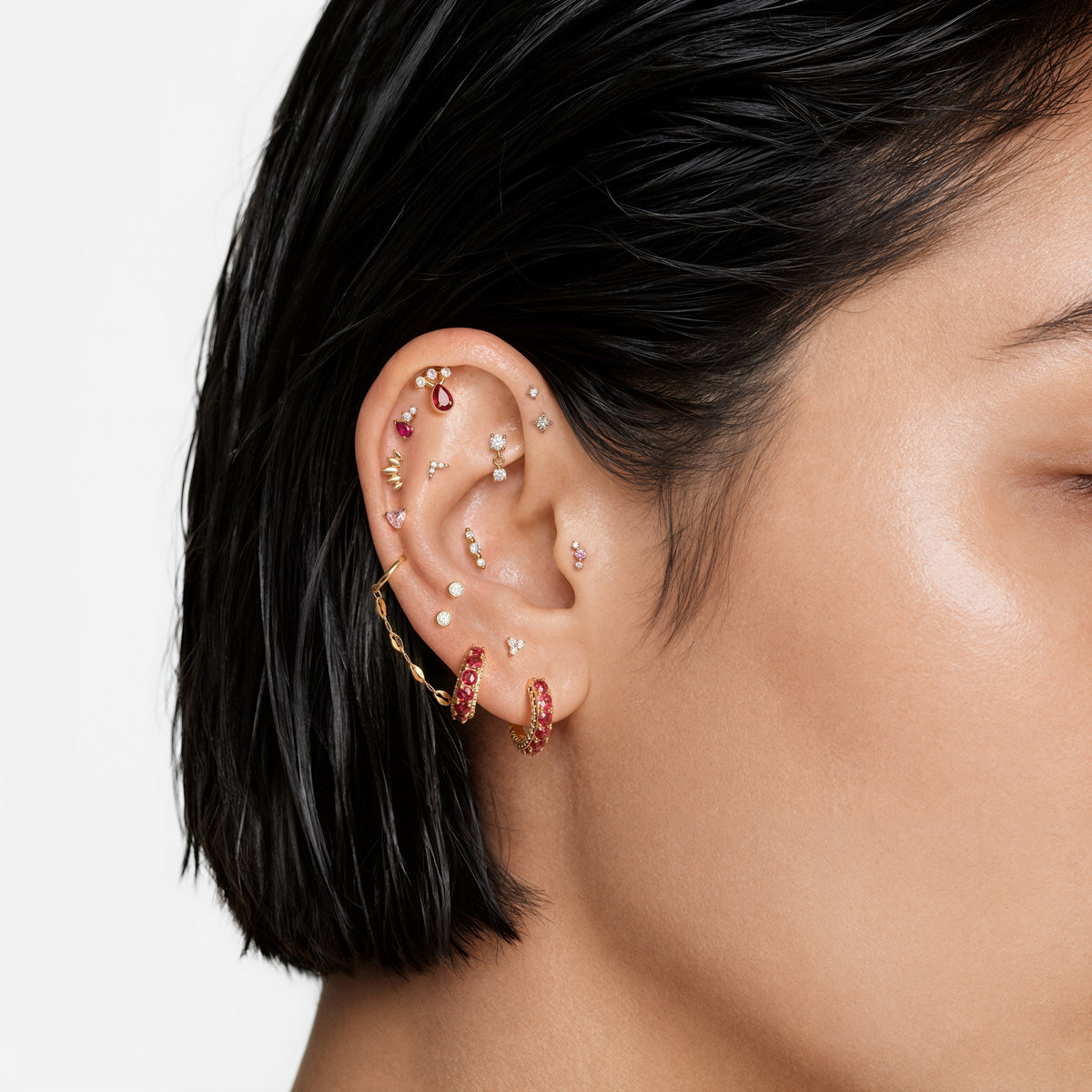 this image shows an earscape featuring a Golden Titanium pear flatback with a pink cz stone. 