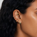 This image shows an earscape featuring the golden titanium baguette flatback with three green cz stones.