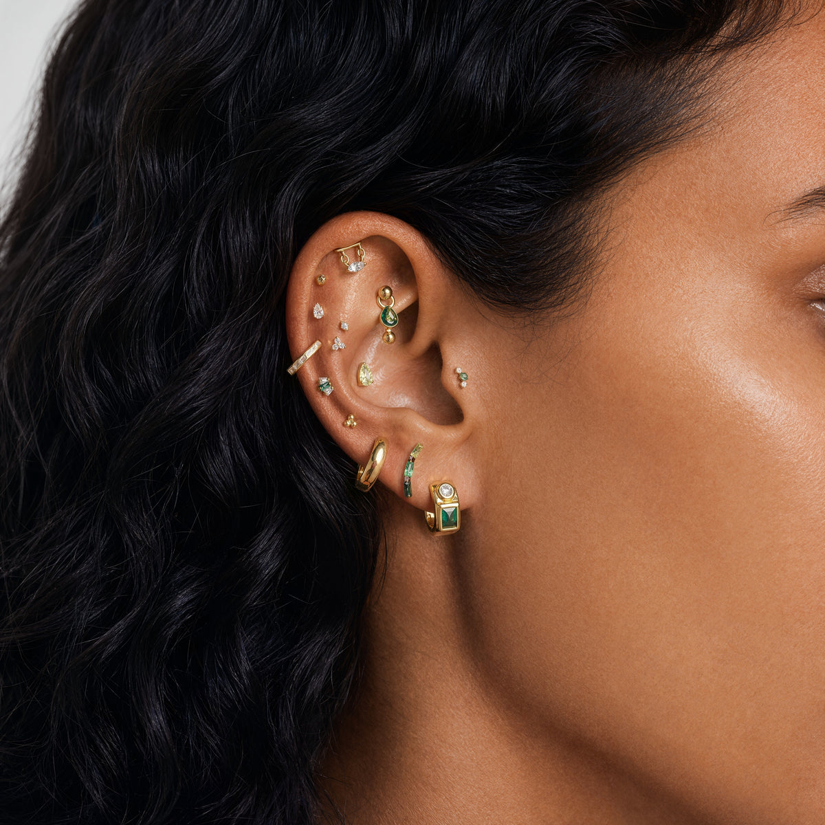 This image shows an earscape featuring the golden titanium baguette flatback with three green cz stones.