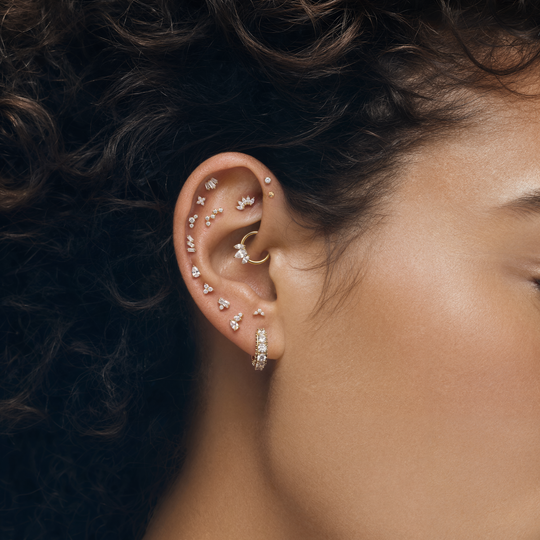 This image shows an earscape featuring gold micro flatback earrings, clicker and huggie 