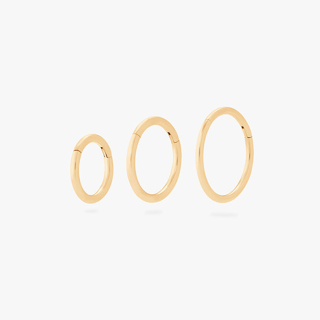 Three gold hoop earrings in different sizes, arranged horizontally on a light gray background.