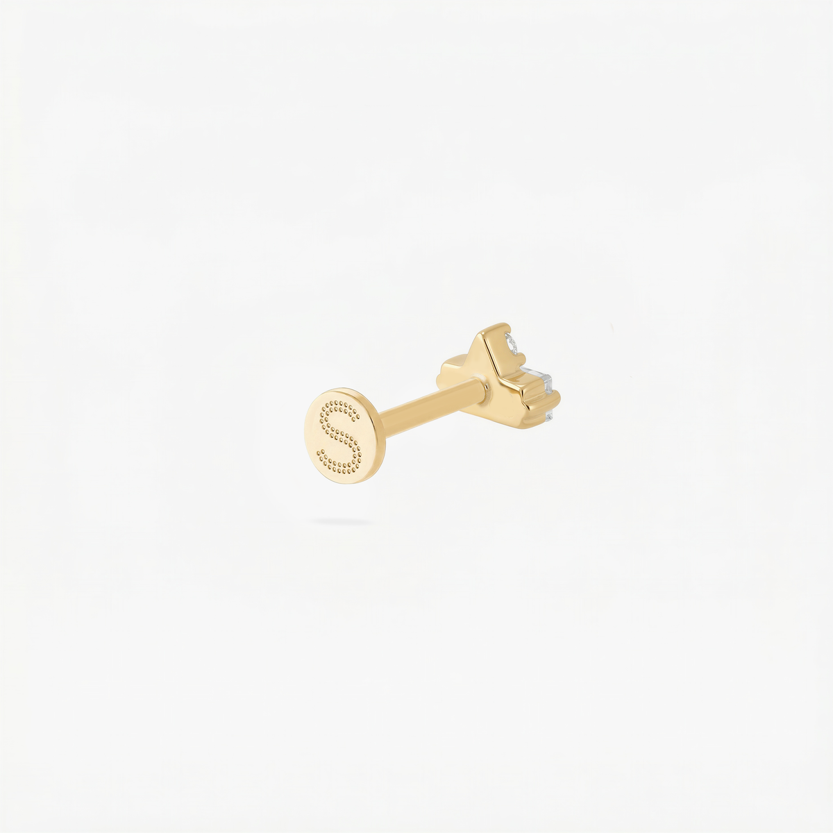 Back angle of a gold flatback with an engraved 'S' on the post