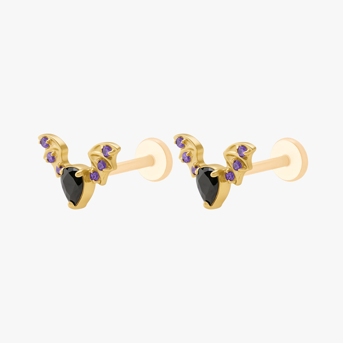 This image shows the side view of a pair of the golden titanium bat flatbacks with a center black cz stone and purple mini cz stones on the wings 