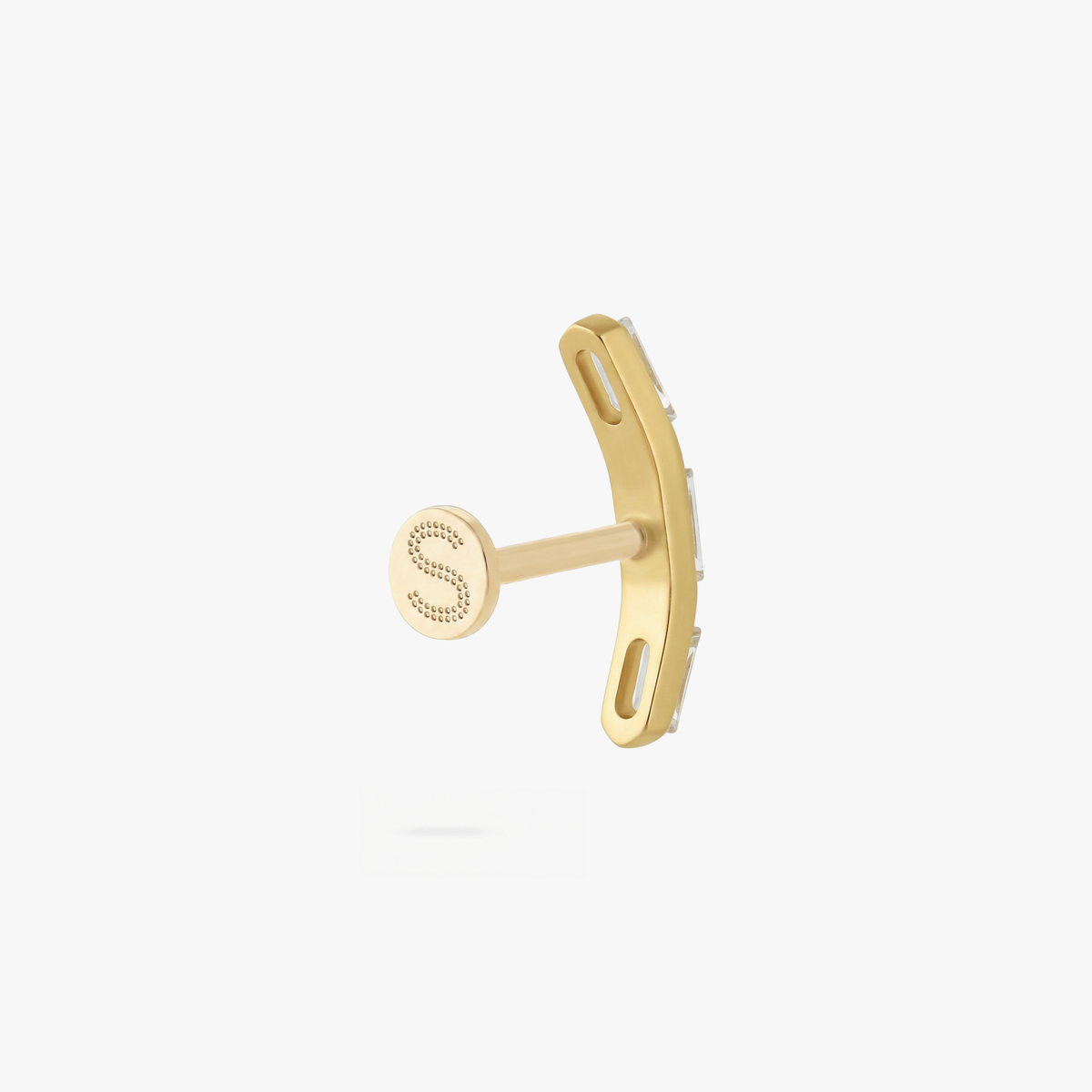 This is an image of a gold toned flatback stud that is in the shape of a curved bar and consists of three baguette cut, clear CZ stones.