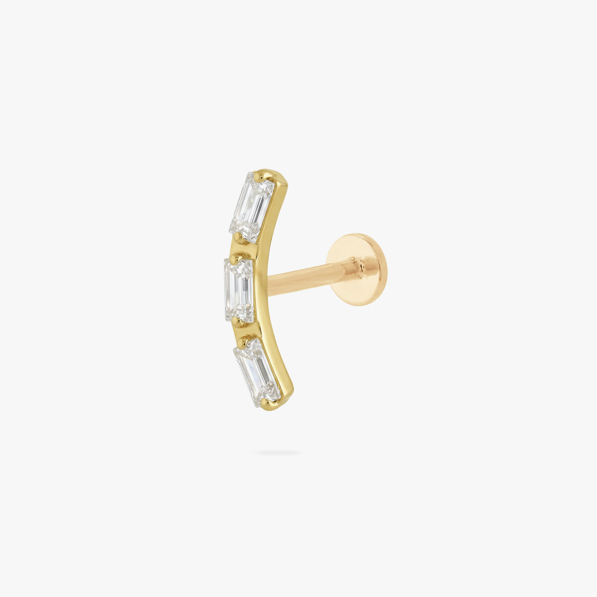 This is an image of a gold toned flatback stud that is in the shape of a curved bar and consists of three baguette cut, clear CZ stones.