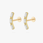 This is an image of a pair of gold toned flatback studs that are in the shape of two curved bars and each consist of three baguette cut, clear CZ stones.