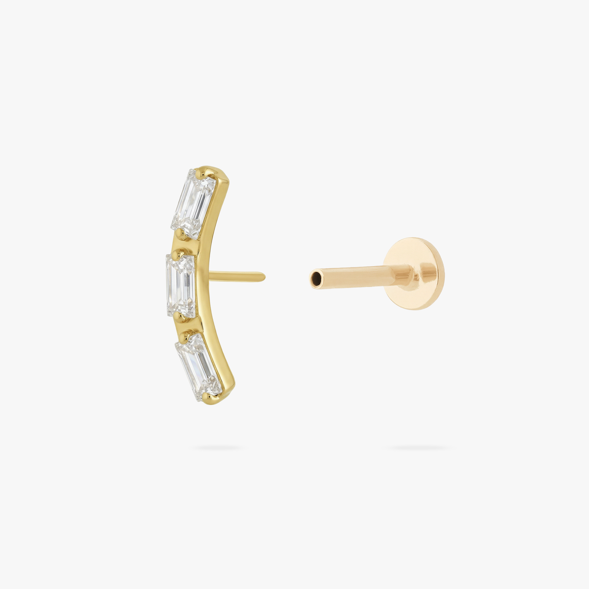 This is an image of a gold toned flatback stud that is in the shape of a curved bar and consists of three baguette cut, clear CZ stones.