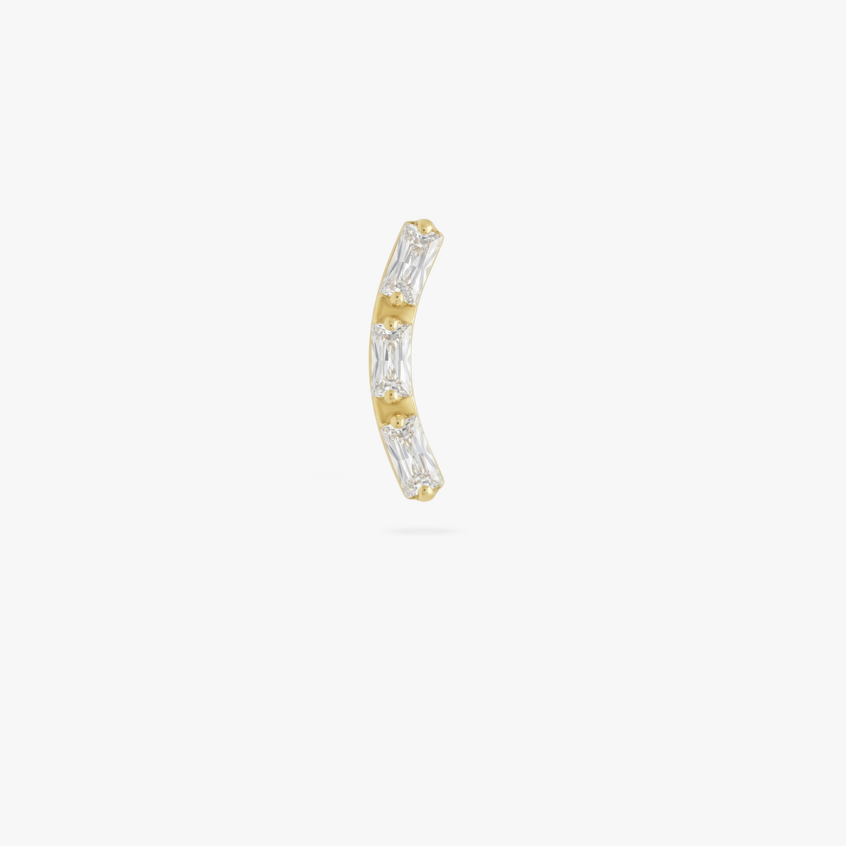 This is an image of a gold toned flatback stud that is in the shape of a curved bar and consists of three baguette cut, clear CZ stones.