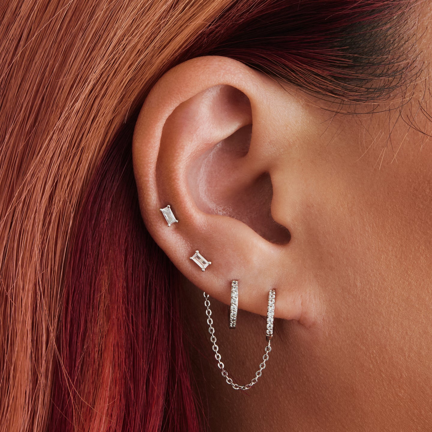 An image of a silver/clear mini pave huggie with a connector chain to an open 4mm wide jump ring on ear. [hover] color:null|silver/clear
