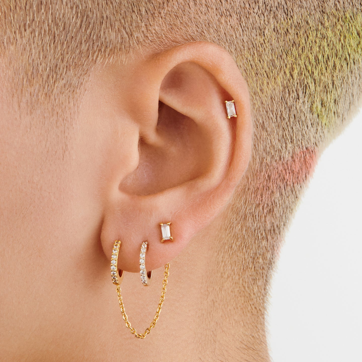 An image of a gold/clear mini pave huggie with a connector chain to an open 4mm wide jump ring on ear. [hover] color:null|gold/clear