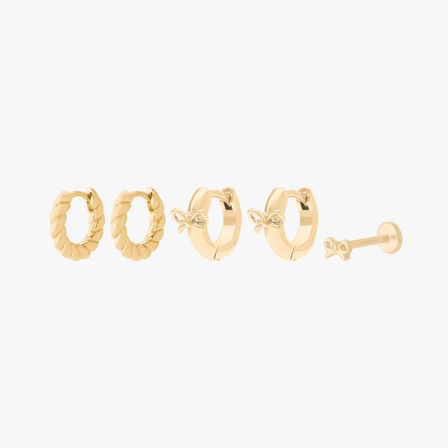 earscape set including a pair of chunky french twist huggies, a pair of micro bow huggies, and a bow flatback stud in gold color:null|gold