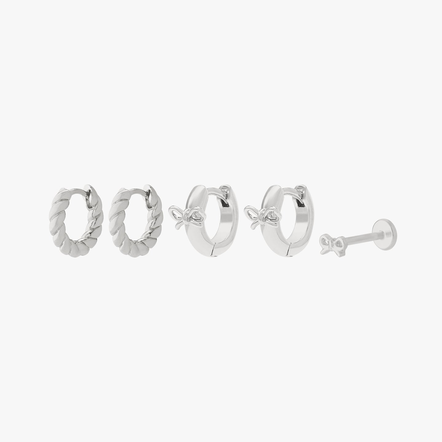 earscape set including a pair of chunky french twist huggies, a pair of micro bow huggies, and a bow flatback stud in silver color:null|silver