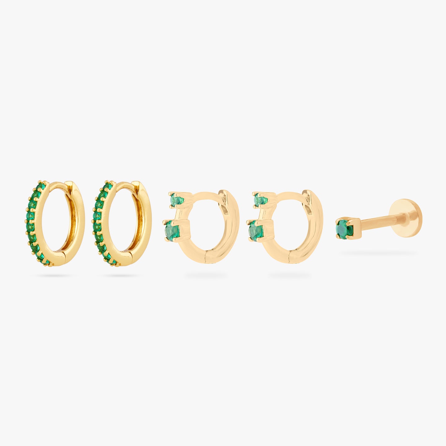 set including a pair of mini pave huggies, a pair of micro duo cz huggies, and a mini cz flatback stud in gold with green stones color:null|gold/green