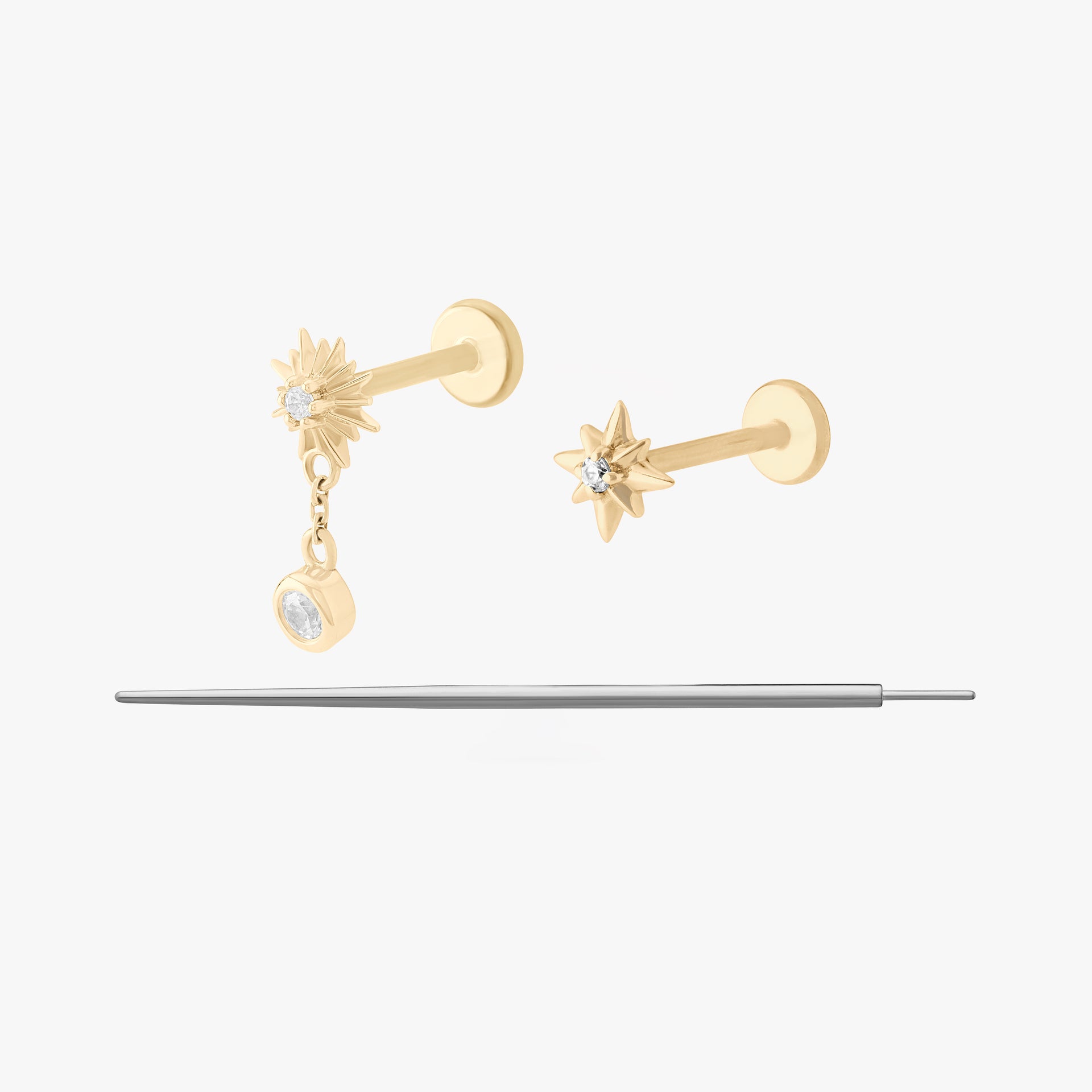This image displays a set of two 14K gold flatback studs and a flatback insertion tool. The two earrings included in this set are the 14K Twinkle Clear Flatback Stud in gold/clear, and the 14K Twinkle Dangle Flatback Stud in gold/clear.