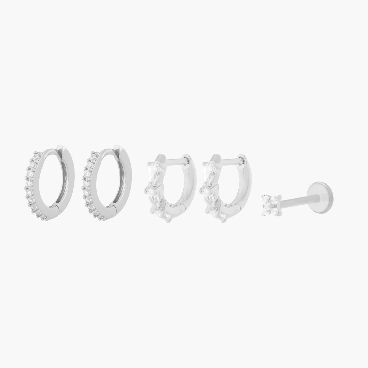 This Pave Starter Set includes two mini pave huggies, two mini pave pear huggies, and one pave x flatback stud. These styles are all silver-toned, and have clear CZ stone accents.