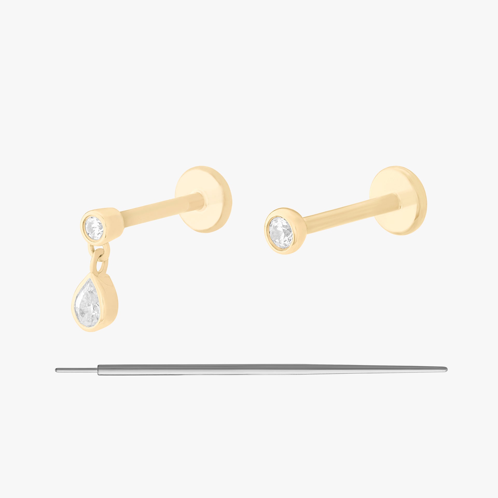 This is an image of the 14K Bezel Set. This image displays a 14K Bezel Pear Dangle Flatback Stud, as well as a 14K Bezel Flatback Stud and an insertion tool.