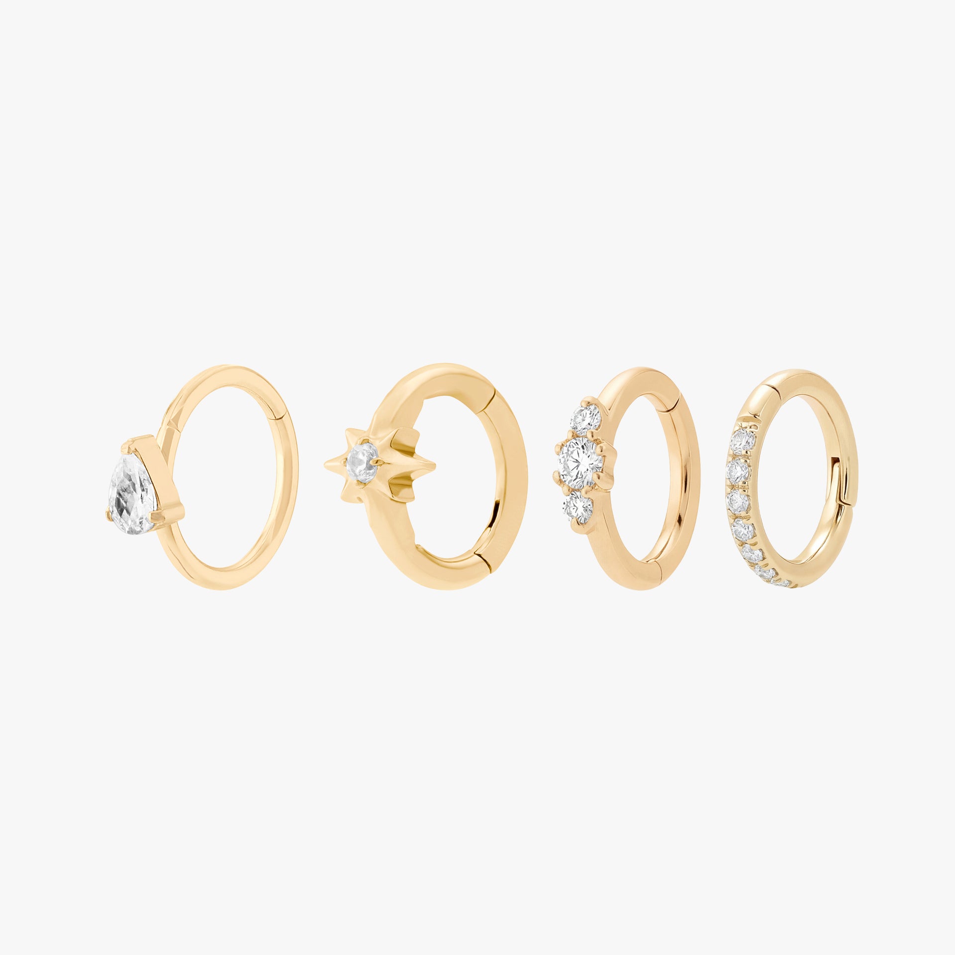 This is an image displaying a gold-toned Micro Clicker Set. This set includes one of each of the following: A Pear CZ Clicker, a Pave Clicker, a Twinkle Clicker, and a Stacked CZ Clicker.