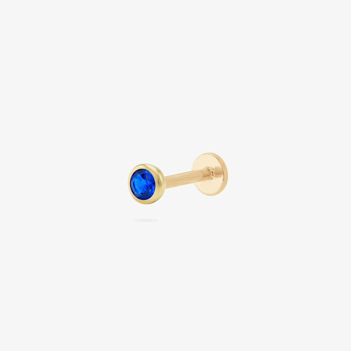 This is an image of a gold toned flatback stud with a 3mm, bezel set blue CZ stone. 
