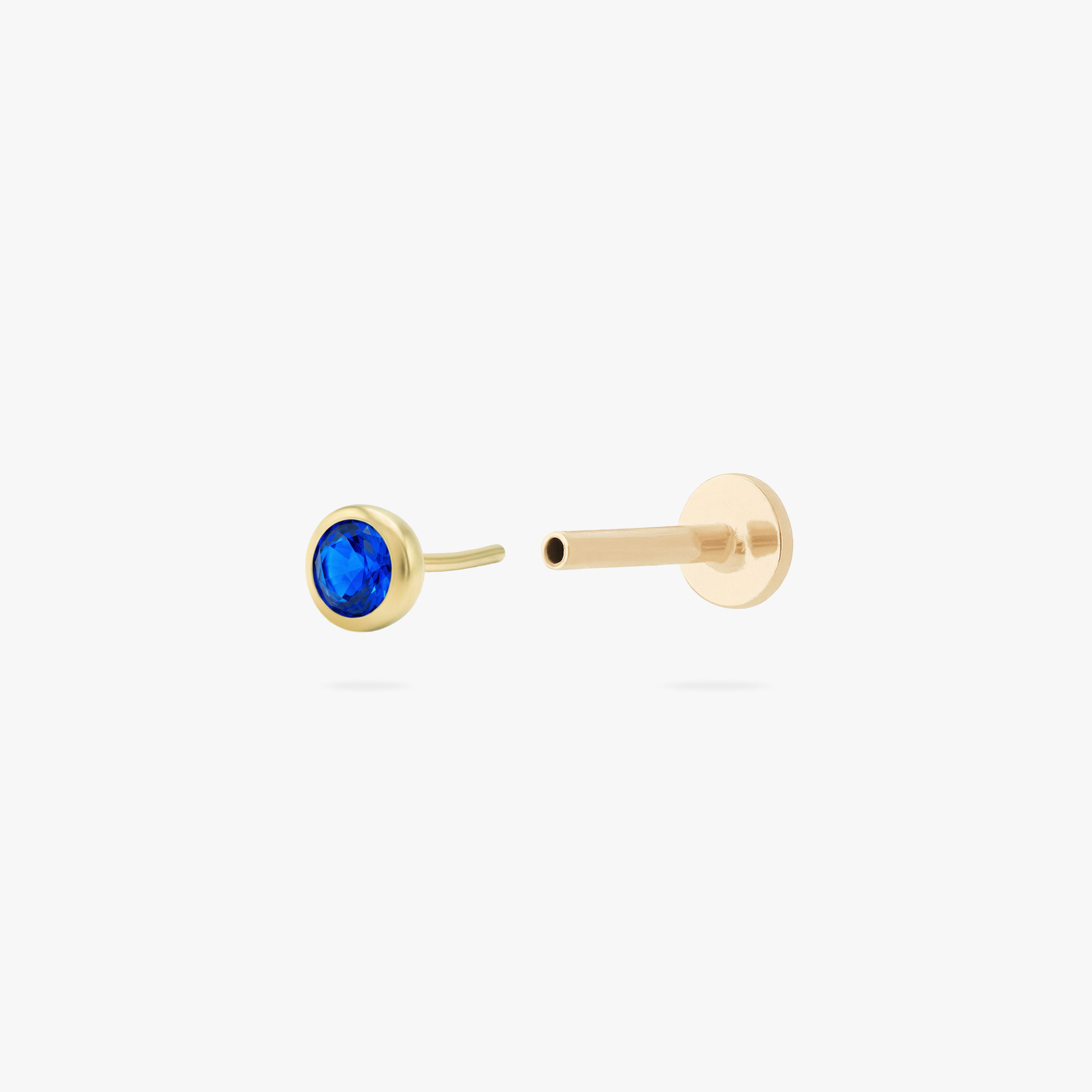 This is an image of a gold toned flatback stud with a 3mm, bezel set blue CZ stone. - Alternative view 2