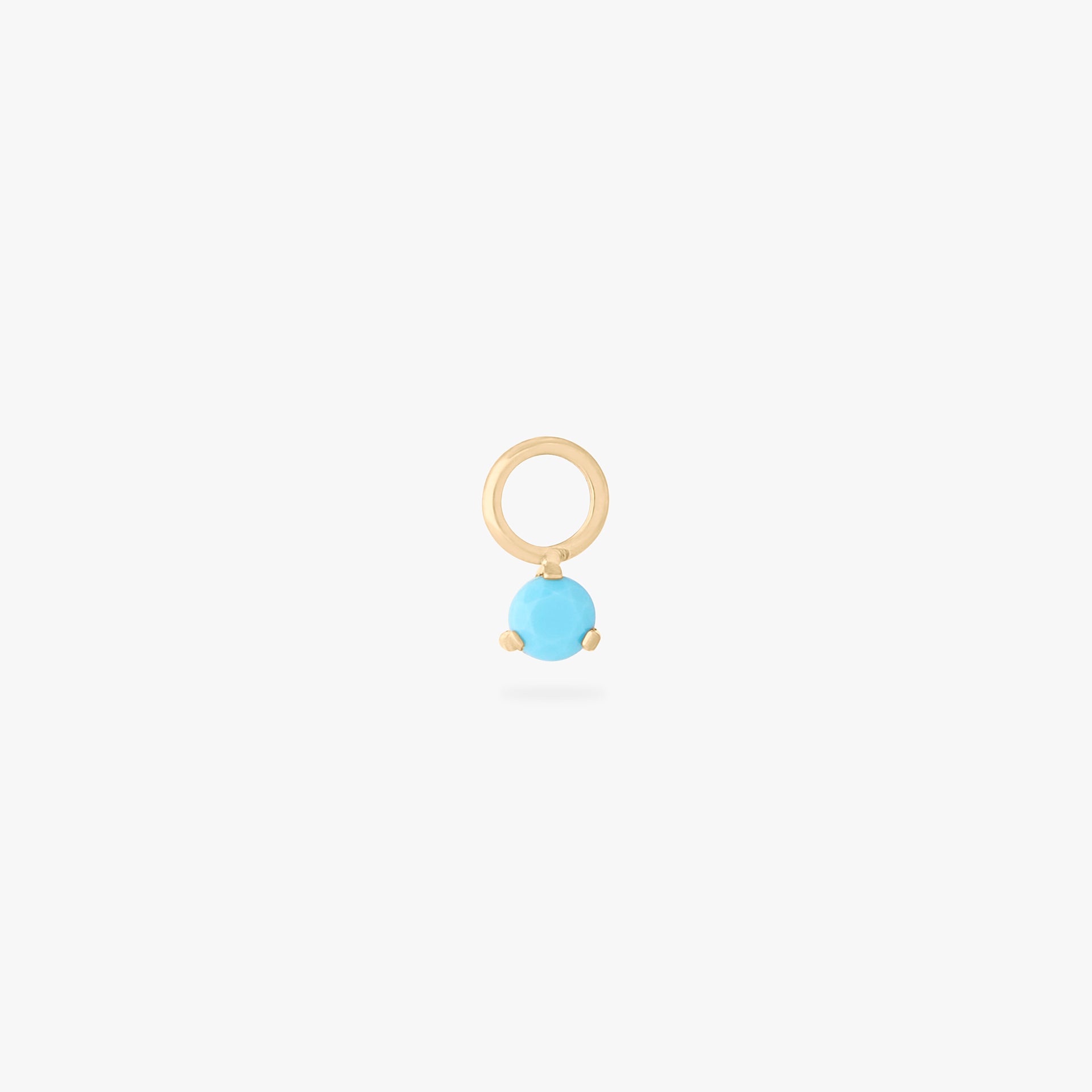 This is an image of a gold toned titanium clicker charm with a turquoise CZ against a white background. - Main view