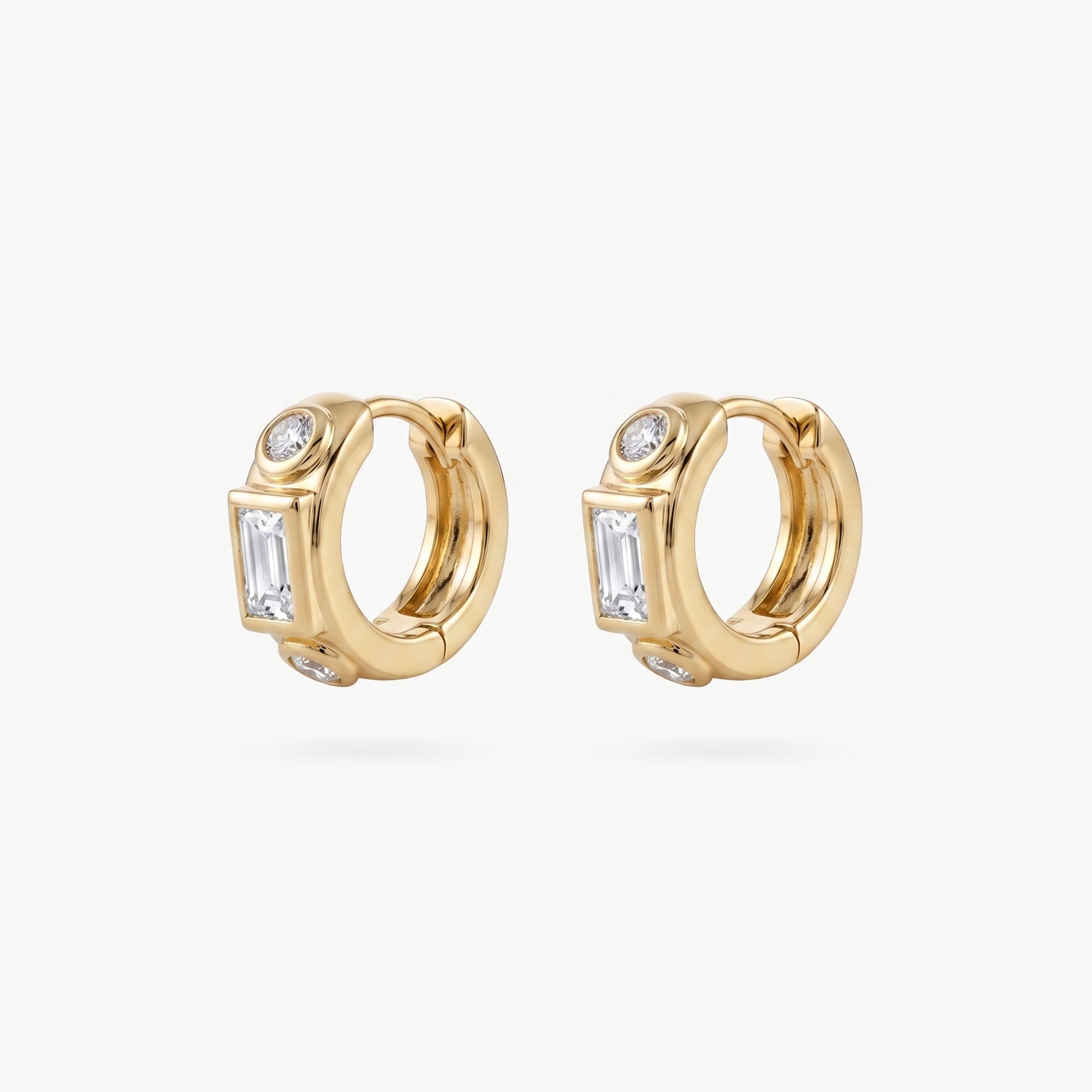 This image shows the front view of a pair of 14k gold plated huggies with three clear cz stones. One square in the middle and two circular stones on the outside. - Pair view