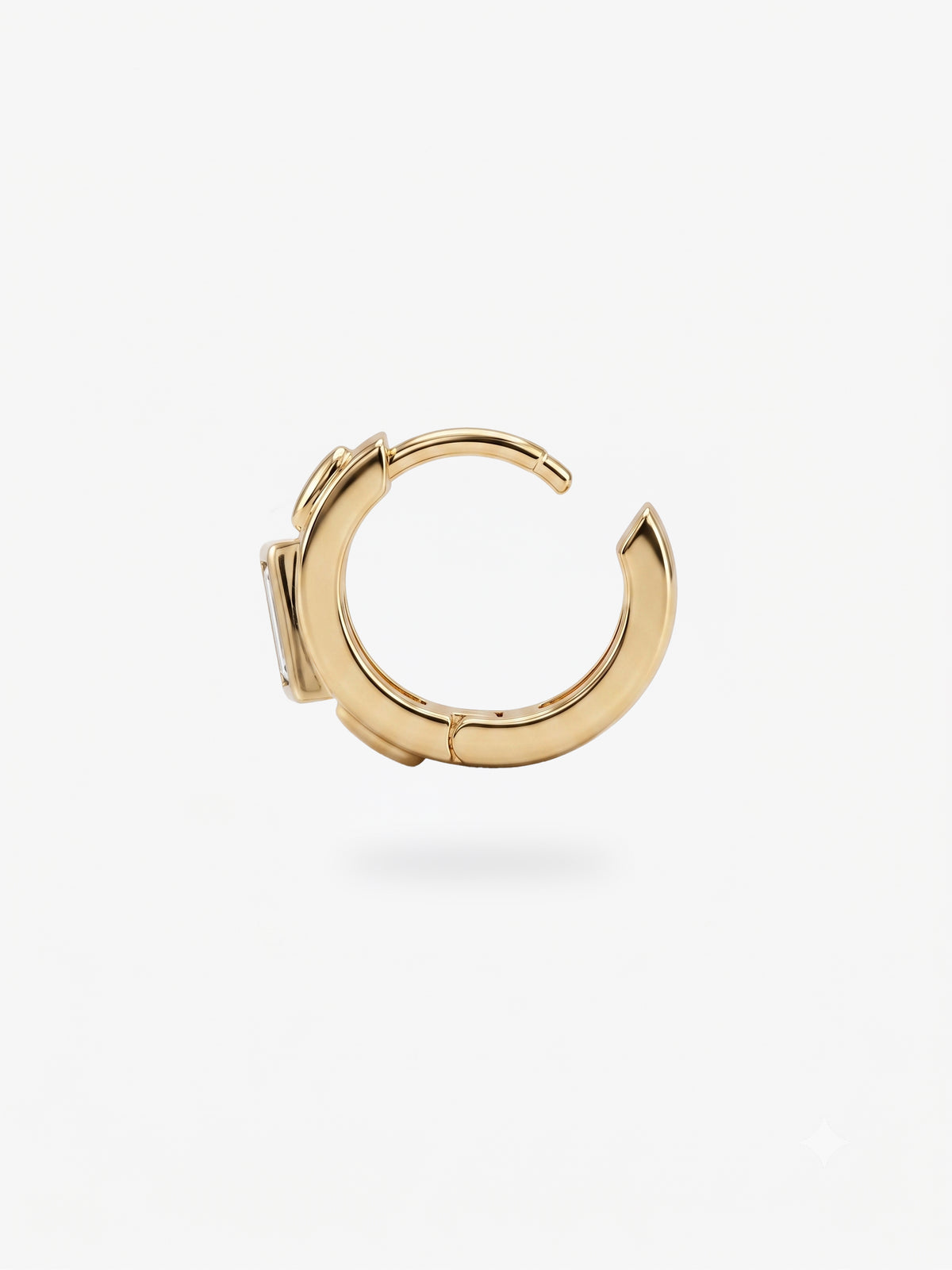 This image shows the profile view of a 14k gold plated huggie with three cz stones. One green square in the middle and two clear circular stones on the outside.