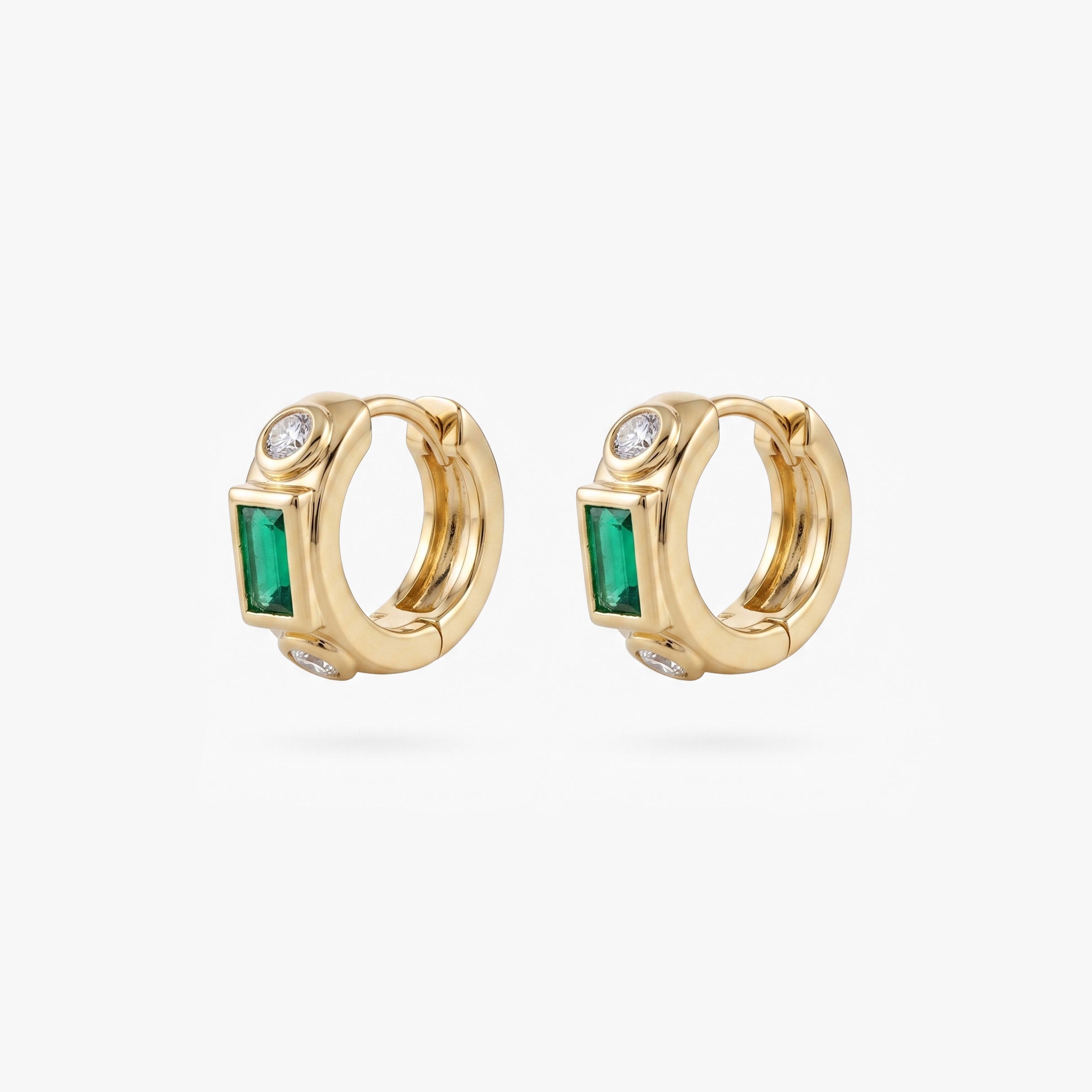 This image shows the front view of a  pair of 14k gold plated huggies with three cz stones. One green square in the middle and two clear circular stones on the outside. - Pair view
