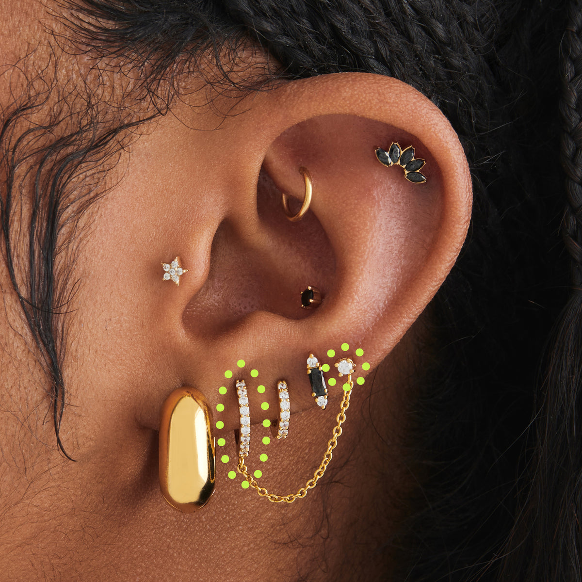 This image shows an earscape featuring a gold plated pave huggie conected to a stud by a connector chain with clear cz stones