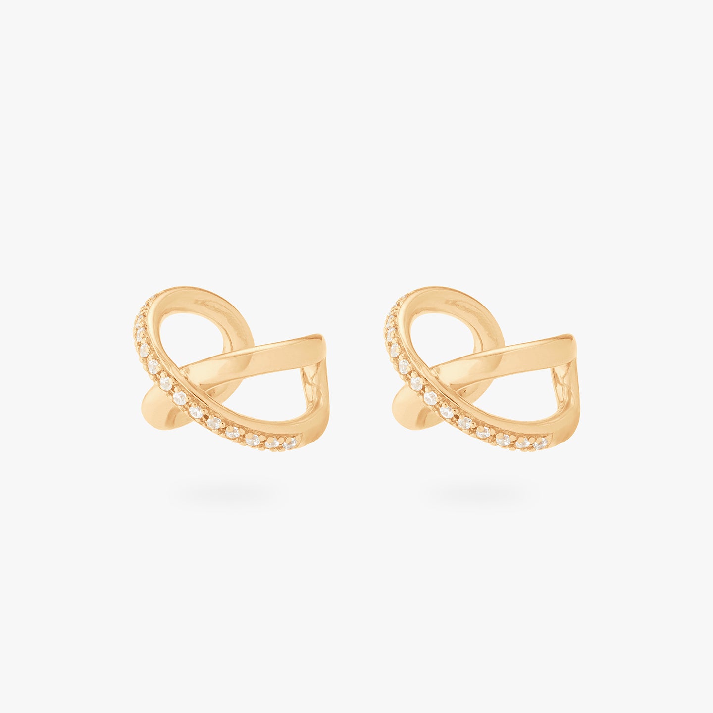 This is an image of a pair of gold twist cuffs that have one side of the twist diagonally lined with gold/clear CZs. [pair] color:null|gold/clear